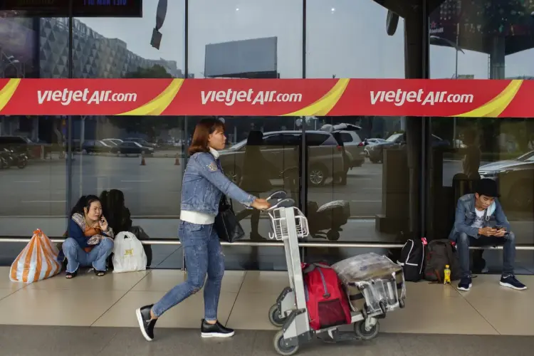 Một hành khách đẩy xe hành lý qua biển hiệu VietJet tại sân bay quốc tế Tân Sơn Nhất, TP.HCM Ảnh: Maika Elan/Bloomberg
