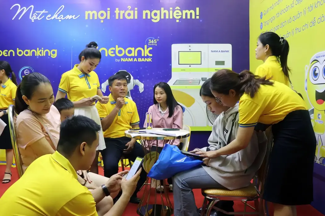 Các nhân viên Ngân hàng Nam Á Bank hướng dẫn người dân sử dụng dịch vụ thanh toán không dùng tiền mặt. Hình ảnh: Tường Quân – TTXVN 